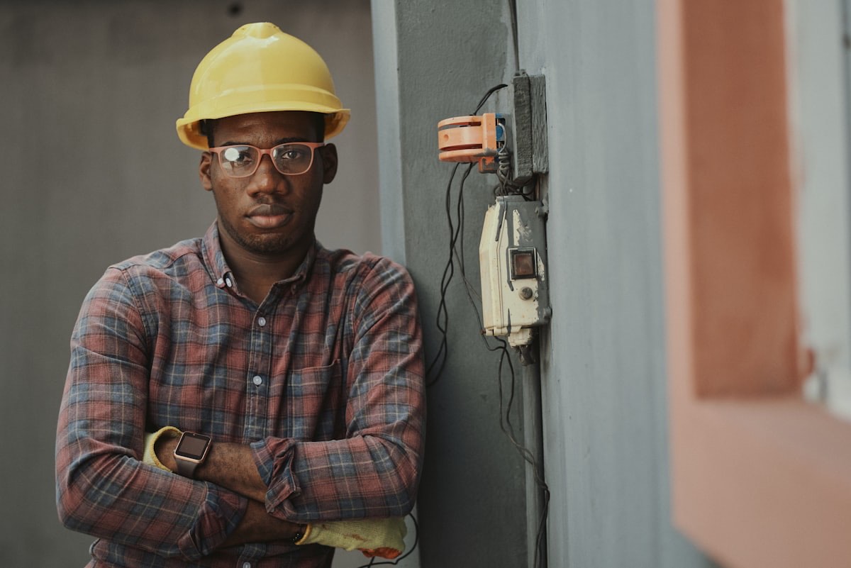 An electrician on site beside an electrical enclosure