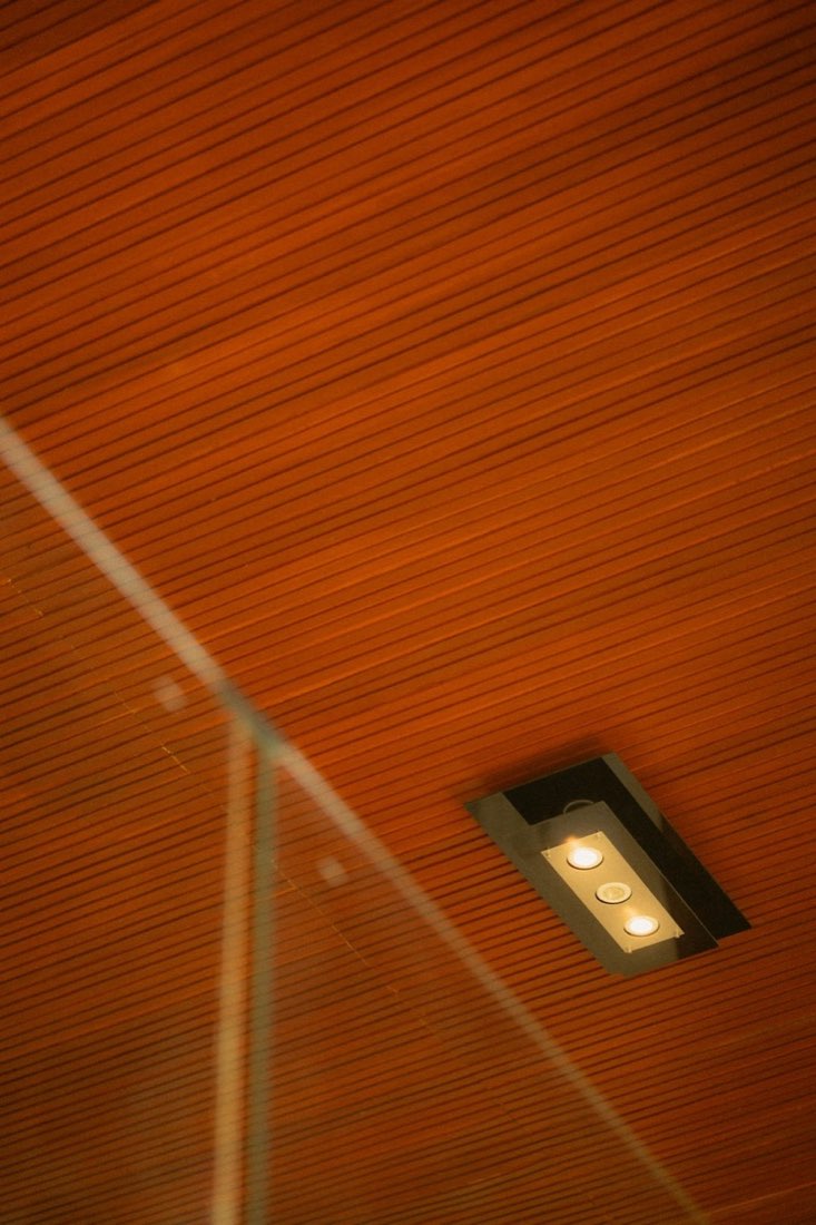 A recessed spotlight fitted into a timber-clad ceiling