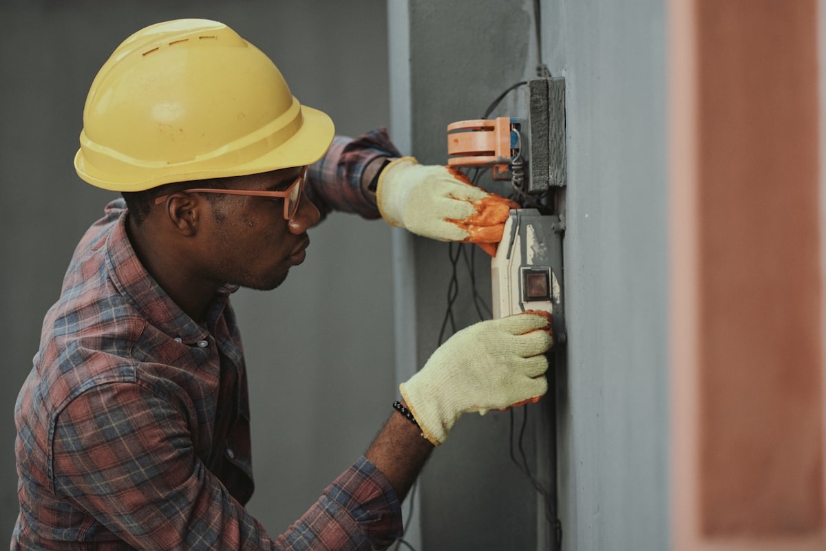 An electrician in protective gear working on an electrical enclosure