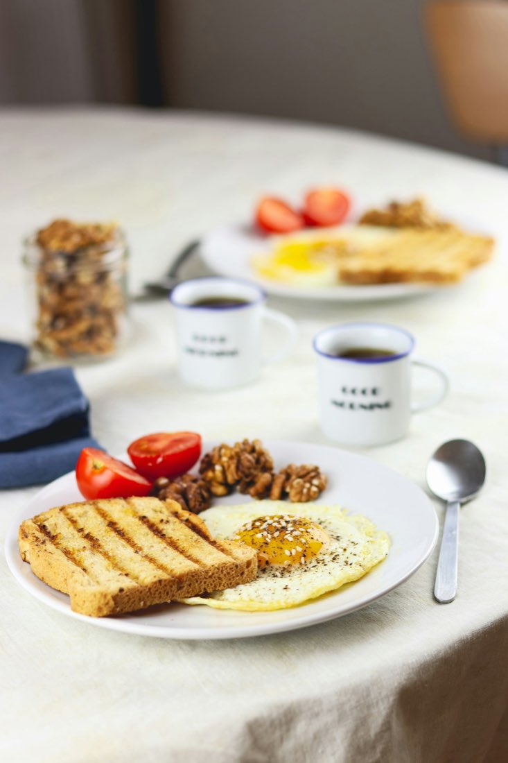 A bright breakfast plate of toast, egg and tomatoes with coffee