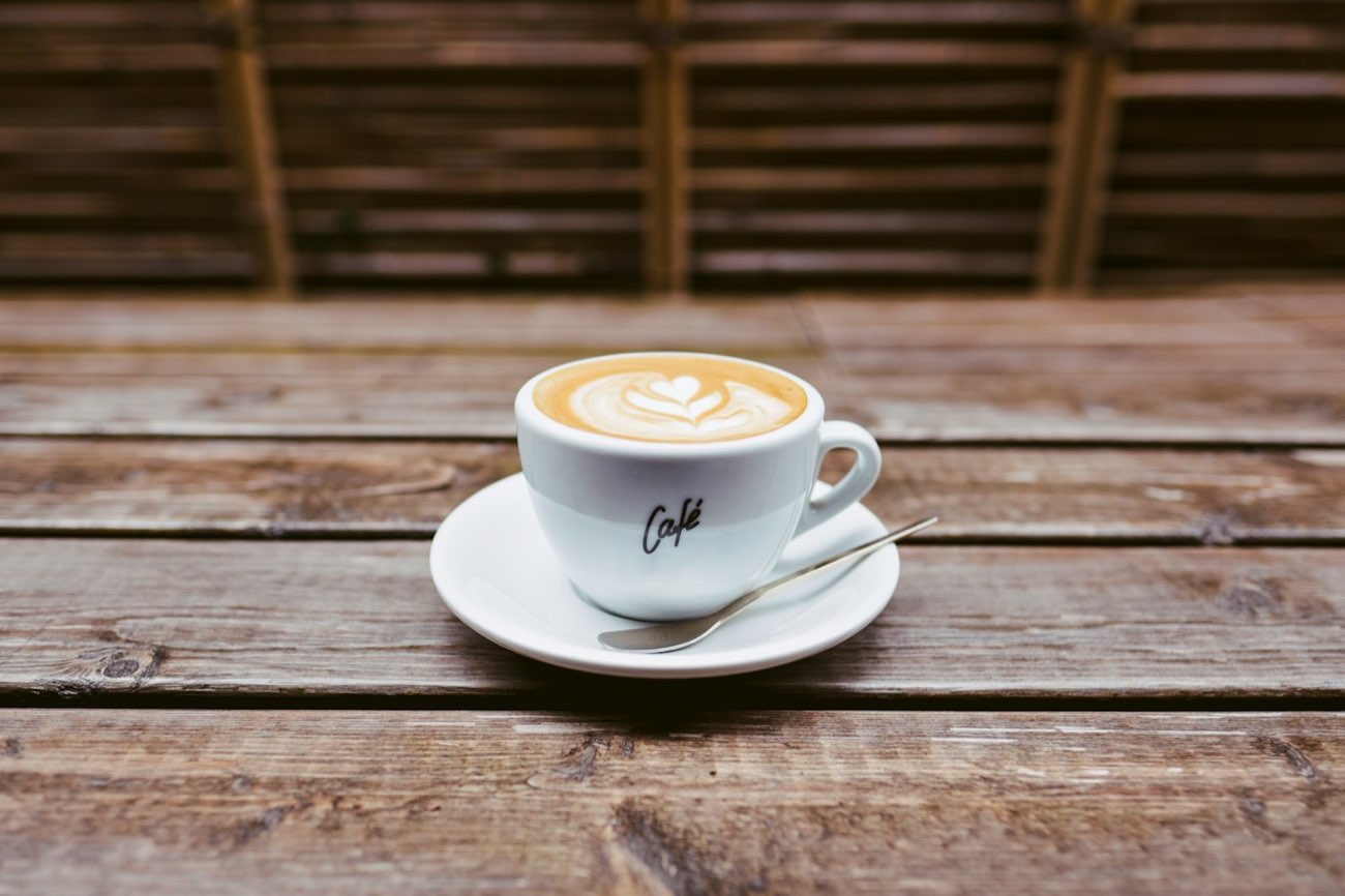 A flat white on a weathered wooden table