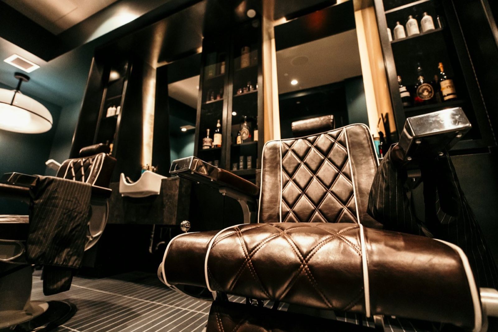 The interior of a premium barbershop with a quilted leather chair in warm, low light