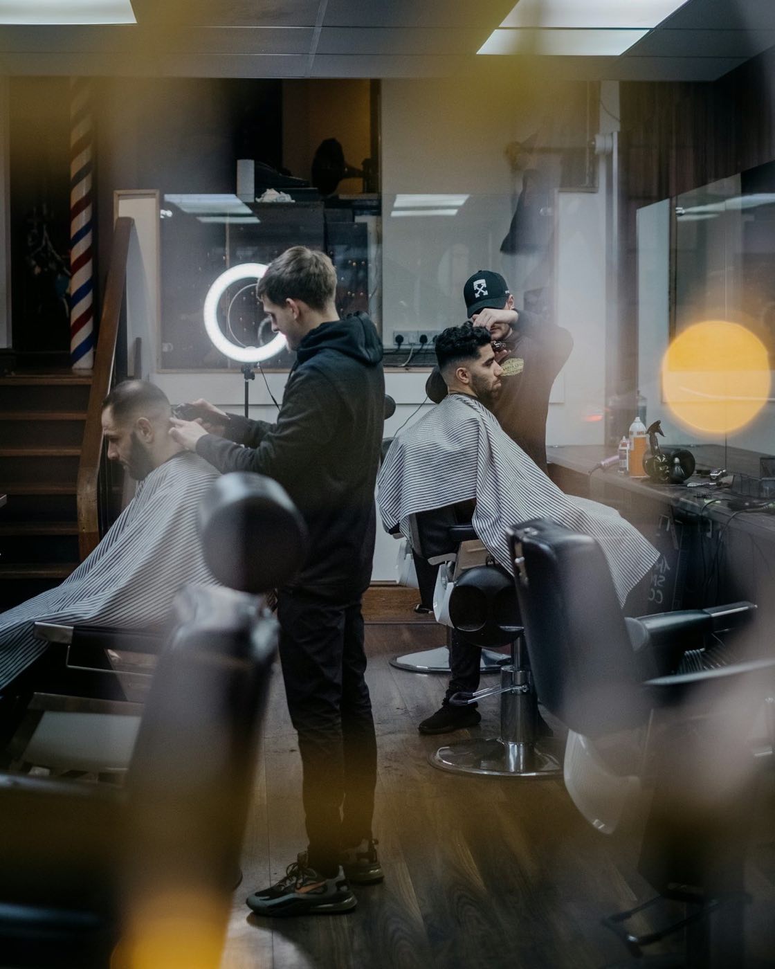 A busy independent barbershop scene in warm light